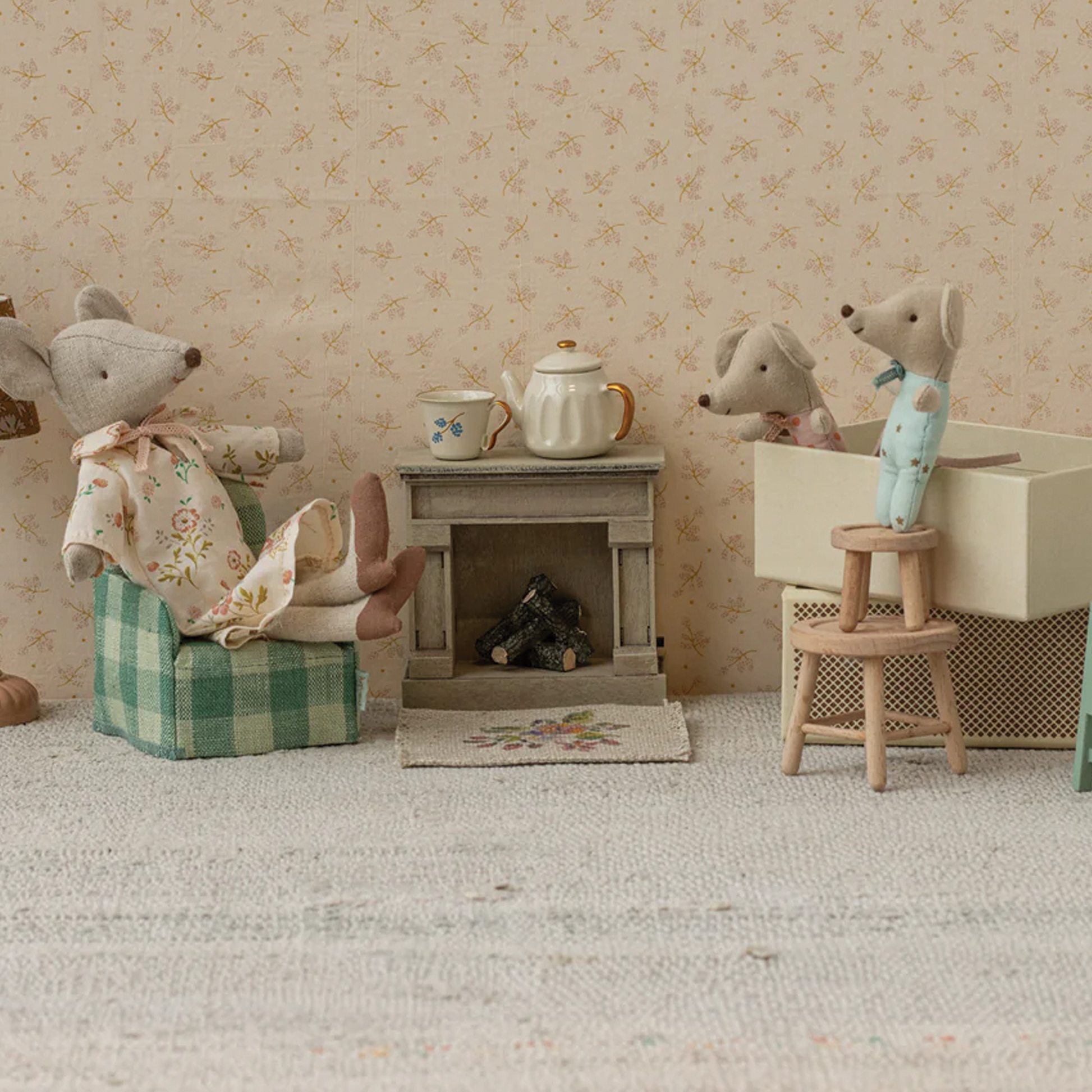 Miniature diorama with toy mice and furniture against a floral wallpaper background